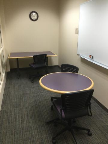 A round table and a rectangular table in small study room. Three chairs.