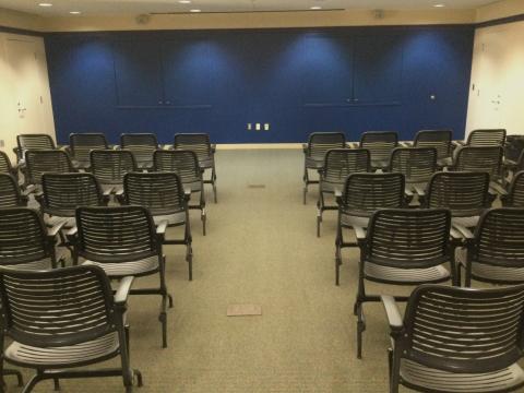 Room with rows of chairs facing front with an aisle up the middle.