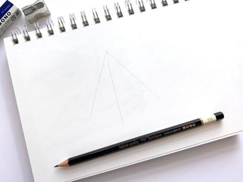 Sketch pad with faint lines forming a triangle, pencil sitting on the sketchpad parallel to the bottom, eraser and sharpenter in top left corner above the sketchpad